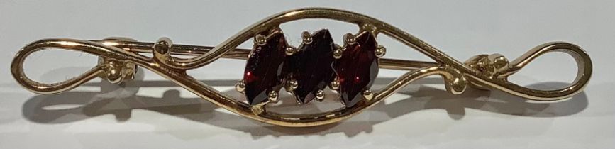 A 9ct gold bar brooch, set with three faceted oval garnets, 4.75cm wide, marked 375, 3.4g