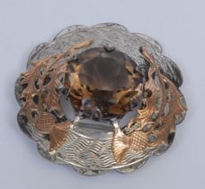 A Scottish silver and gold coloured metal shaped circular plaid brooch, applied with thistles and