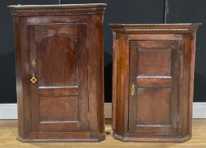A George III oak corner cabinet, 94cm high; another, slightly later and smaller, 80.5cm high (2)