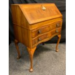 A reproduction walnut bureau, serpentine shaped front, hinged fall door to top enclosing a fitted