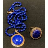 A 9ct gold mounted lapis lazuli oval panel dress ring, 6.4g Gross; similar bead pedant necklace,