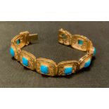 An Egyptian turquoise and yellow metal nine section bracelet, indistinctly marked, 31.9g gross