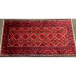 A North Persian Meshed Belouch rug / carpet, hand-knotted in deep red and black, 250cm x 132cm.