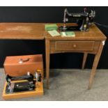 A Singer B.A.K electric sewing machine table with foot control, with manual; another Singer sewing