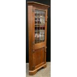 A Nigel Griffiths floor-standing oak corner cupboard, out-swept cornice, glazed, leaded door to