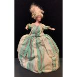 An Early 20th century bisque head tea cosy doll, painted features, arms poised, green stripped and