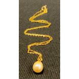 A gold coloured metal and pearl drop pendant, gold coloured metal chain
