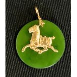 A circular jade and gold coloured metal pendant, set to centre with a horse