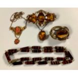 A Victorian pinchbeck type metal brooch, set with a row of three amber glass stones, with further