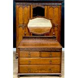 An oak two-piece bedroom suite, comprising wardrobe and dressing chest, each frieze carved with