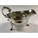 A late Victorian silver sauce boat, shaped border, acantus capped scroll handle, three slender