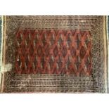 A Middle Eastern woollen rug or carpet, stylised geometric motifs and borders in tones of red and