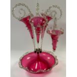 A Victorian cranberry glass epergne, the circular dished base with three cranberry flutes and