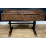 A 17th century style oak trestle table, rectangular top carved with a flower head, a figure,