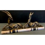 An art deco spelter model, recumbent gazelles male and female, on veined black and white marble