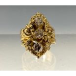 An unusual diamond ring, the shaped floral crest set with three round brilliant cut diamonds, each