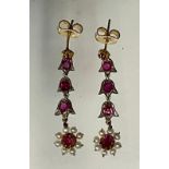 A pair of ruby and seed pearl floral drop earrings, each articulated drop of three ruby set links