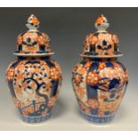 A pair Japanese Imari jars and covers, decorated with traditional panels of flowers, roundels and