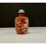 A Chinese carved stone snuff bottle, in relief with a bird feeding from blossoming prunus, green