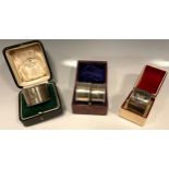 A pair of silver napkin rings, E Edmonds, Birmingham 1917, cased; another wavy banded, Mappin & Webb