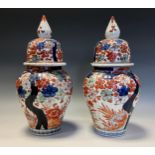 A pair of Japanese fluted ovoid vases and covers, painted in the Imari palette with flowers, 35cm