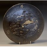 A Japanese iron and mixed metal circular plate, decorated with busy figures and dwellings in a