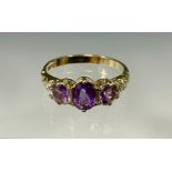 A 9ct gold and amethyst ring, the central oval cut stone flanked by two smaller round cut stones