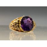 A 20th century amethyst ring, oval amethyst crown claw set above textured shoulders, yellow metal