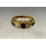 An 18ct gold diamond and sapphire ring, the central sapphire divided by two round brilliant cut