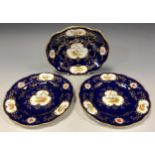 A Coalport oval dish and pair of circular plates painted with panels of birds and flowers, cobalt
