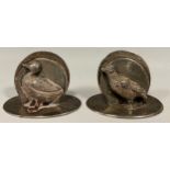 A pair of George V silver novelty menu holders, applied with a duck and a game bird, oval bases, 4cm