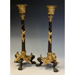 A pair of 19th century parcel-gilt and dark patinated bronze tripod candlesticks, cast with lizards,