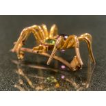 A spider brooch, amethyst and peridot green body, pink cabochon eyes, unmarked gold coloured metal