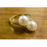A diamond and pearl dress ring, two creamy white cultured pearls, approx 7mm diameter, set between