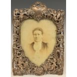 A Victorian silver photograph frame, the front embossed with cavorting cherubs and mythical beasts