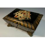 A Regency penwork sarcophagus games box, the hinged cover decorated with playing cards, brass