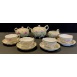 A Japanese porcelain tea set for four, painted and relief decorated with violets and floral buds,