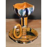 An Art pottery chamber stick, in the manner of Christopher Dresser, glazed in mottled tones of