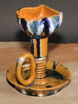 An Art pottery chamber stick, in the manner of Christopher Dresser, glazed in mottled tones of