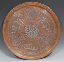 A Middle Eastern silver damascened copper circular tray, inlaid in the Islamic taste with Arabic