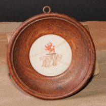 A 19th century porcelain armorial, painted with a crest and monogram, oak frame, 11.5cm diam overall