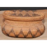 Tribal Art - an African oval basket and cover, worked in two tones with geometric motifs, 14.5cm