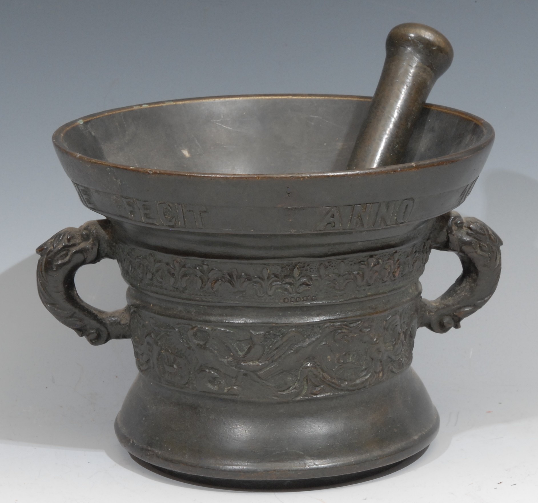 A Dutch bronze pestle and mortar, cast with birds and scrolling foliage, inscribed beneath the rim