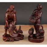 A pair of Chinese hardwood figures, carved as a young fisherman and a girl feeding geese, 25.5cm and