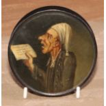 A 19th century papier mache circular snuff box, the cover painted with a ban singing from sheet