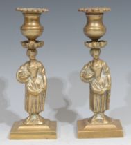 A pair of Regency bronze figural candlesticks, each cast as a young lady gathering flowers,