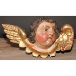 An Italian Baroque polychrome painted and gilt carving, the head of a putto, 28cm wide, 18th/19th