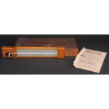 A Negretti & Zambra minimum self-registering thermometer, silvered register, oak mount, 35.5cm long