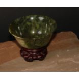 A Chinese spinach jade bowl, 10cm diam, hardwood stand