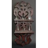 Treen - a softwood spoon rack, possibly Welsh, shaped and pierced with scrolls and a wheel motif,
